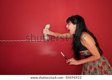 Frustrated Caucasian woman yells on phone call over maroon background