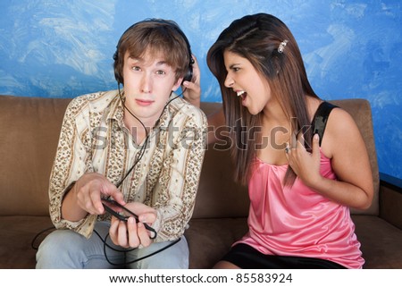 Beautiful young woman yells at boy with headphones