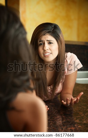 Worried young girl talks with friend at a granite table