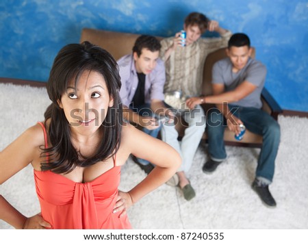 Annoyed young Hispanic woman ignored by three young men playing video games