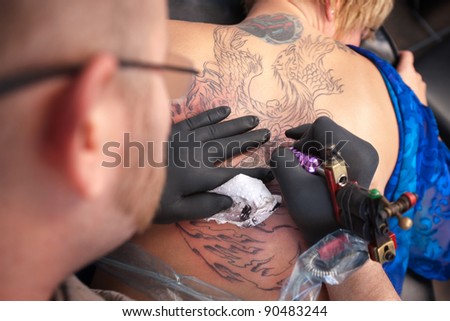 stock photo Male tattoo artist draws a design on back of client