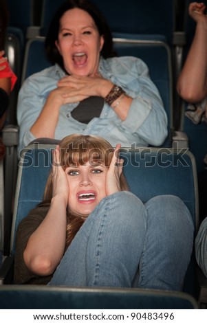 Screaming women watch scary movie in theater