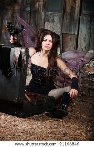 Frustrated Caucasian fairy holds black roses in rustic location