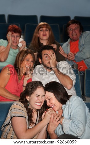 Group of scared people watch horror movie in theater