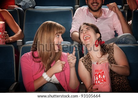 Two pretty young women in the audience laugh together