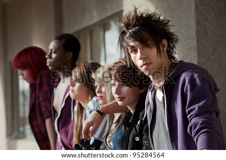 Young punk boy looks at the camera as his friends look away into the distance.