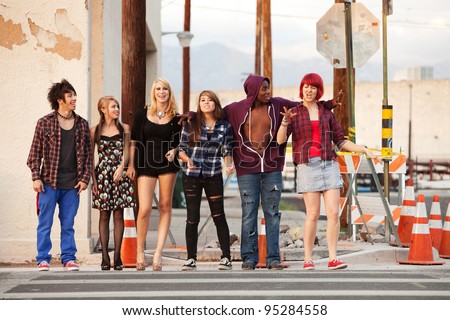 Young and happy gang of teen punks cross the street together.
