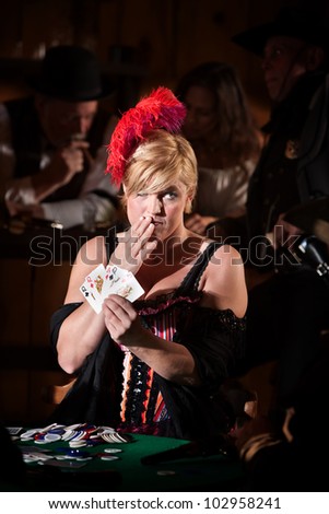 Pretty showgirl with hand over mouth and playing cards