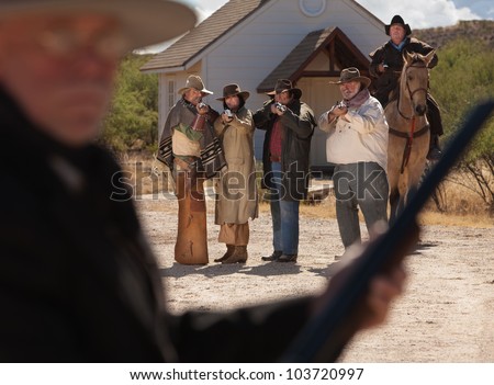 Six old west gunfighters target a man in black