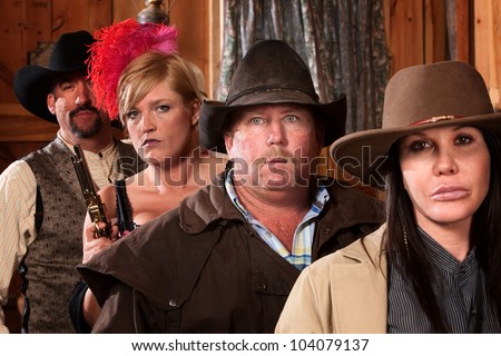 Tough looking cowboy between two mean women in old saloon
