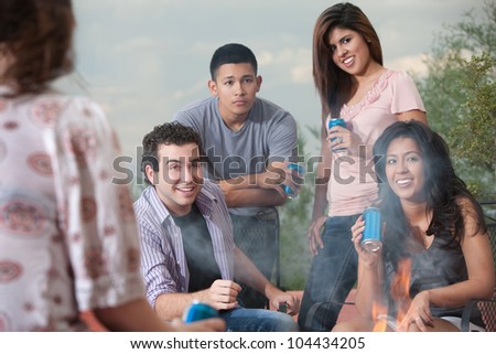Mixed group of young people drinking soda at a campfire