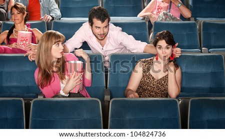 Shocked young women near flirting man in theater
