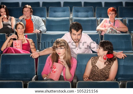 Rude bearded man talking to ladies in a theater