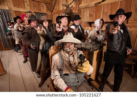 Tough men and women pull out their weapons in a saloon