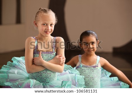 Young ballet student folding arms with friend nearby