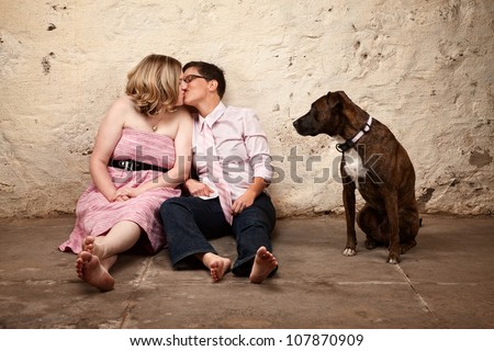 Lesbian kissing couple on floor with pet dog watching