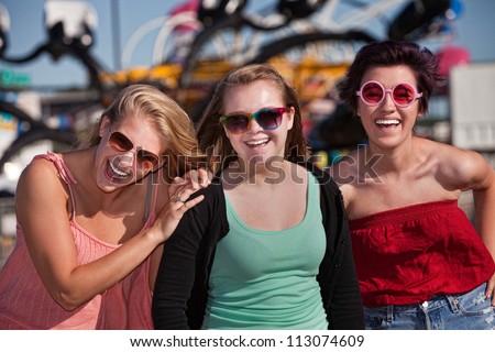 Group of three laughing teenage girls at an amusement park