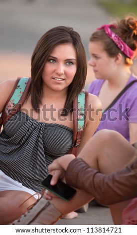 Caucasian female teenager listening to friends sitting on the ground