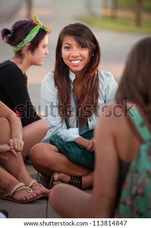 Grinning Filipino girl with friends sitting cross legged