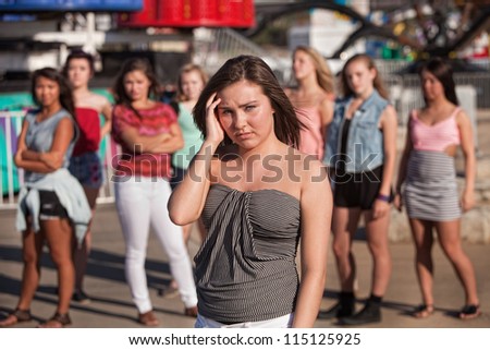 Depressed young woman away from friends at amusement park