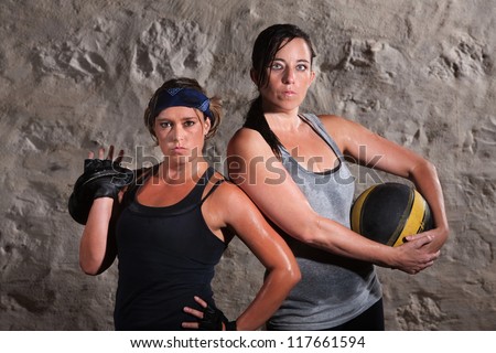 Pair of beautiful women holding boot camp training equipment