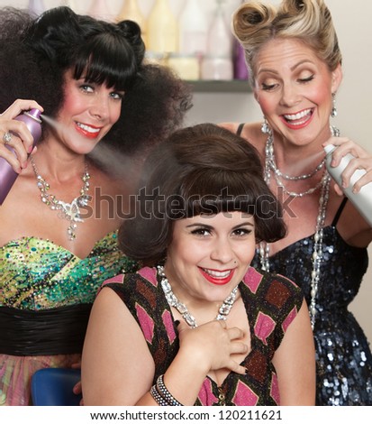 Three happy women playing with hair spray in beauty salon