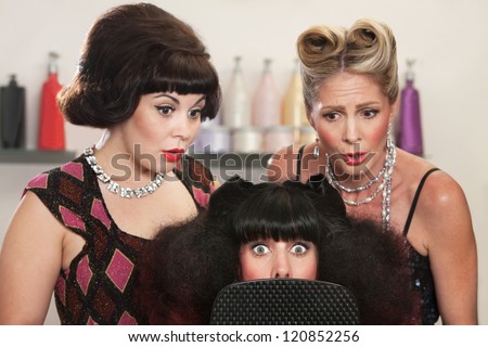 Wide eyed woman behind mirror with two friends in hair salon