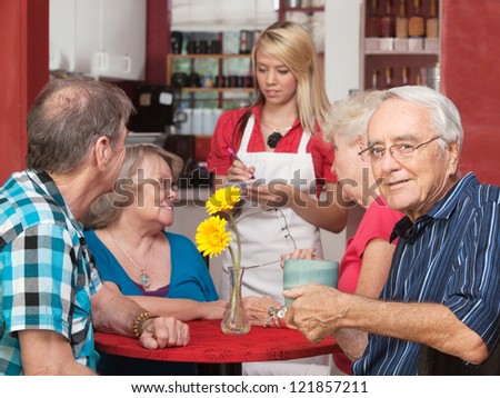 Senior Caucasian male sitting with friends in a cafe