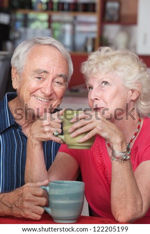 Smiling elderly couple with mugs at a coffeehouse