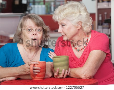 Surprised older woman talking with her friend in a cafe
