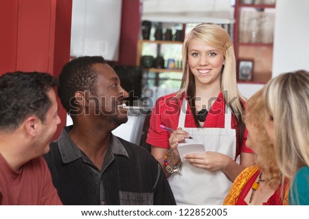 Caucasian waitress taking orders from diverse group of customers