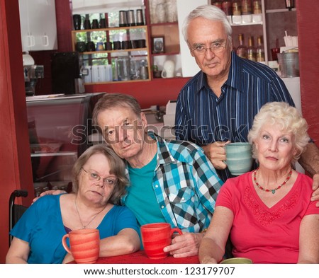 Sad group of four senior citizens in cafe