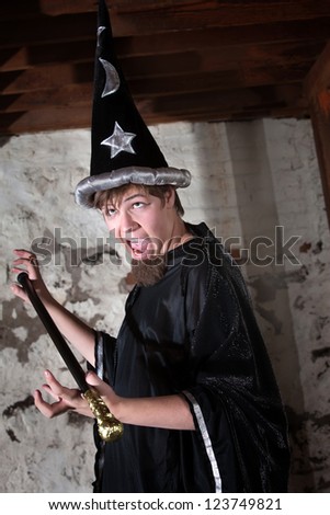 Funny young wizard holding a scepter with eyes rolled up