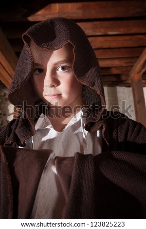 Young magician with folded arms hidden in his cloak