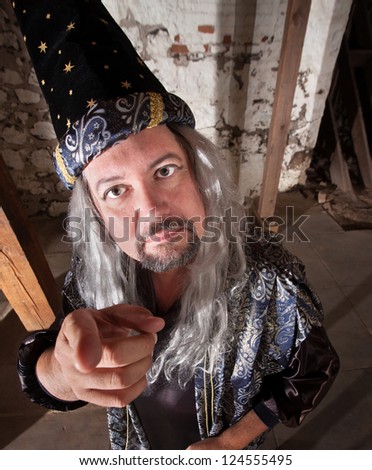 Middle aged serious European male wizard pointing