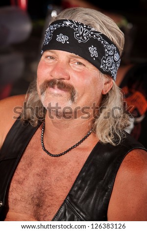 Grinning middle aged man with leather vest and bandanna
