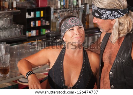 Mature biker gang female admiring man in bar