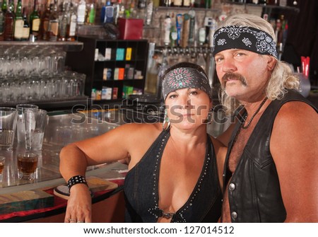 Serious middle aged biker gang couple at bar