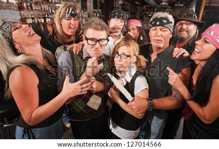 Intimidated nerd couple surrounded by laughing gang with dagger