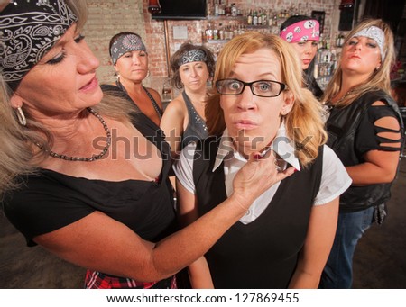 Tough biker gang woman with hand near female nerd\'s neck
