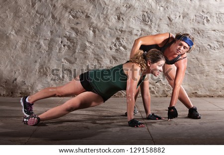 Physical fitness trainer with woman doing right angle pushups