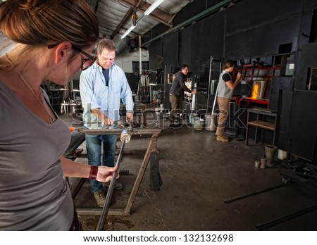 Four men and women busy in a glass making workshop