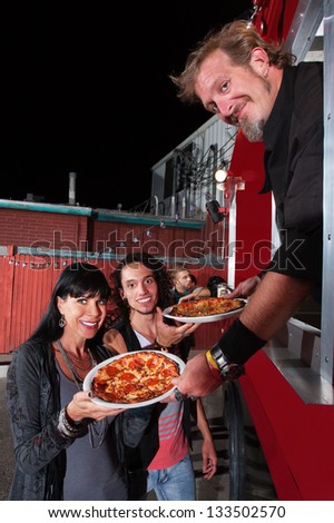 Smiling customers with food truck owner and pepperoni pizza