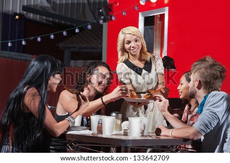 Young mixed woman sharing pizza with friends at cafe