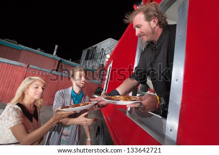 Chef serving carryout pizza from food truck