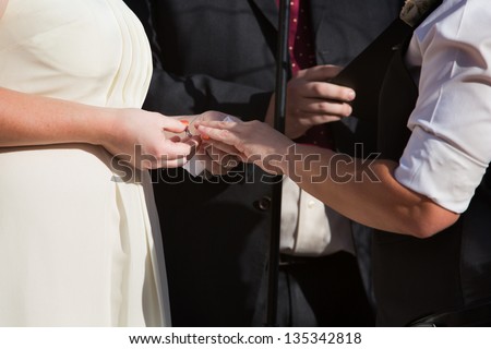 Woman putting ring on finger of partner in civil union