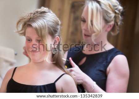 Grinning young woman and adult working on hairdo
