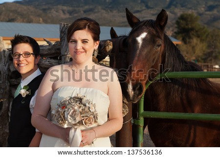 Beautiful same sex couple near horse at ranch