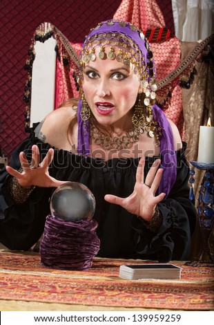 Charming Caucasian woman in headscarf waving hands over crystal ball
