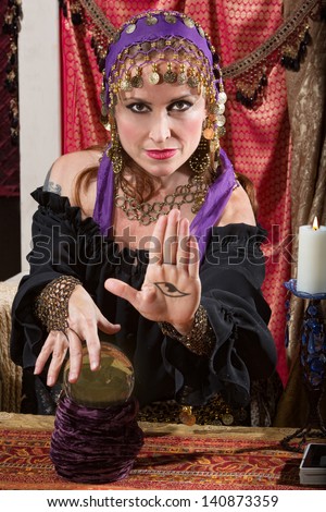 Mysterious female fortune teller showing an evil eye in palm